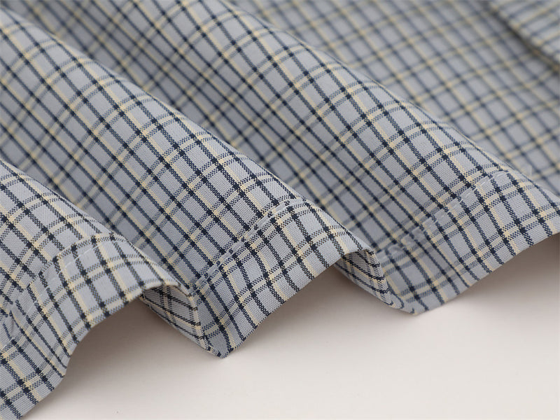 Close-up of three folded shirt hems on gray plaid fabric with light blue and navy checks