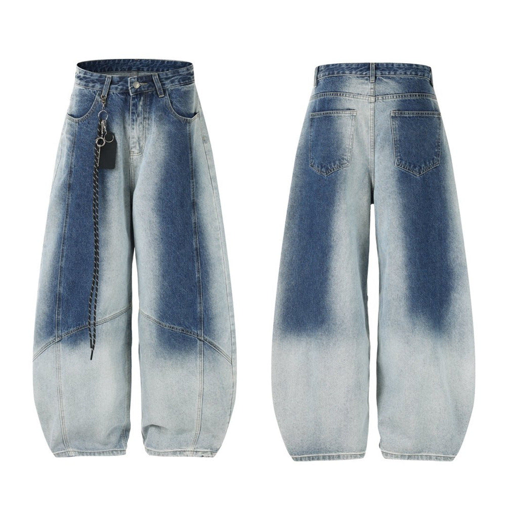 Men's wide-leg gradient washed jeans with deconstructed curved seam paneling and chain keyring detail, shown in faded blue co