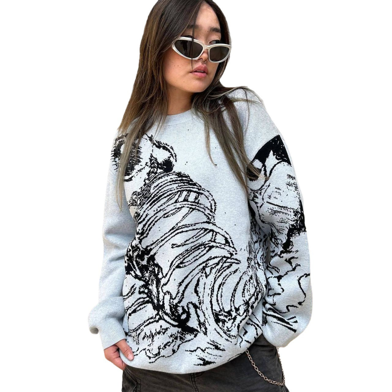 A person wearing Seakoff's Premium Skeleton Ribcage Knit Sweater, featuring a gothic jacquard design, stands with hands in pockets. They have long dark hair and face slightly sideways against a plain background, exuding alternative fashion vibes.