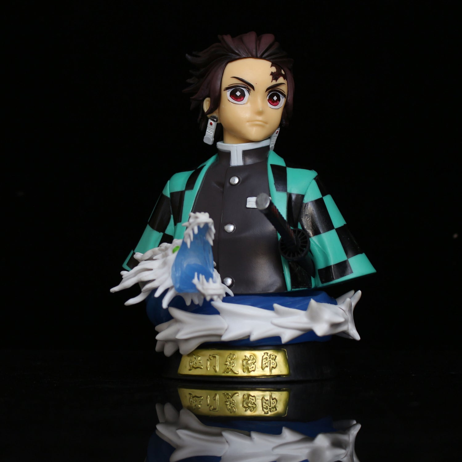 The Demon Slayer Tanjiro Kamado GK Half-Body Action Figure showcases Tanjiro in his green and black checkered robe, along with a sword featuring a blue, water-like effect. He stands on a black base with gold Japanese text, complete with an LED light effect.