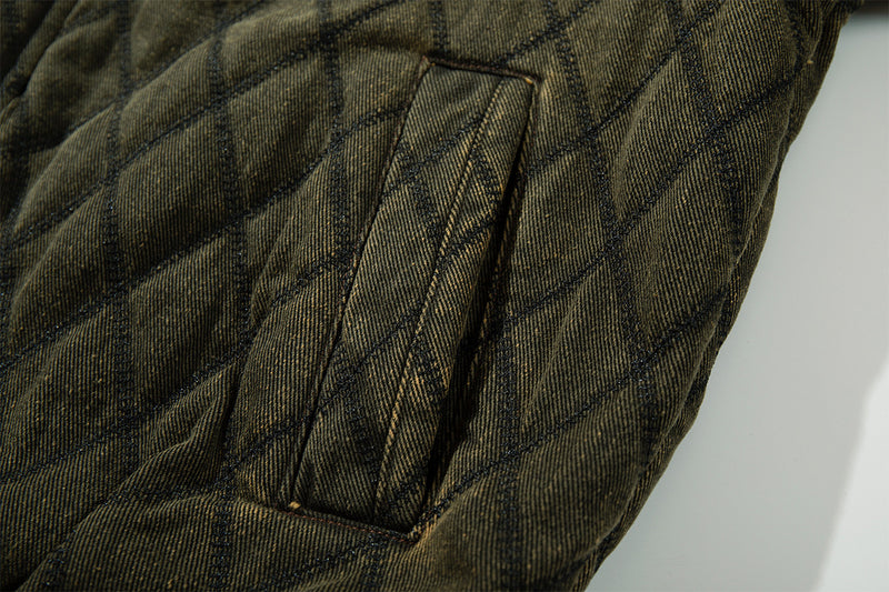 Close-up of the olive green quilted jacket sleeve showing a stitched rectangular pocket