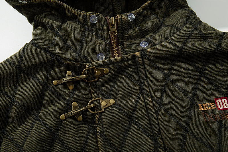 Close-up of an olive quilted jacket front showing toggle closures, zipper, snap fasteners, and chest embroidery