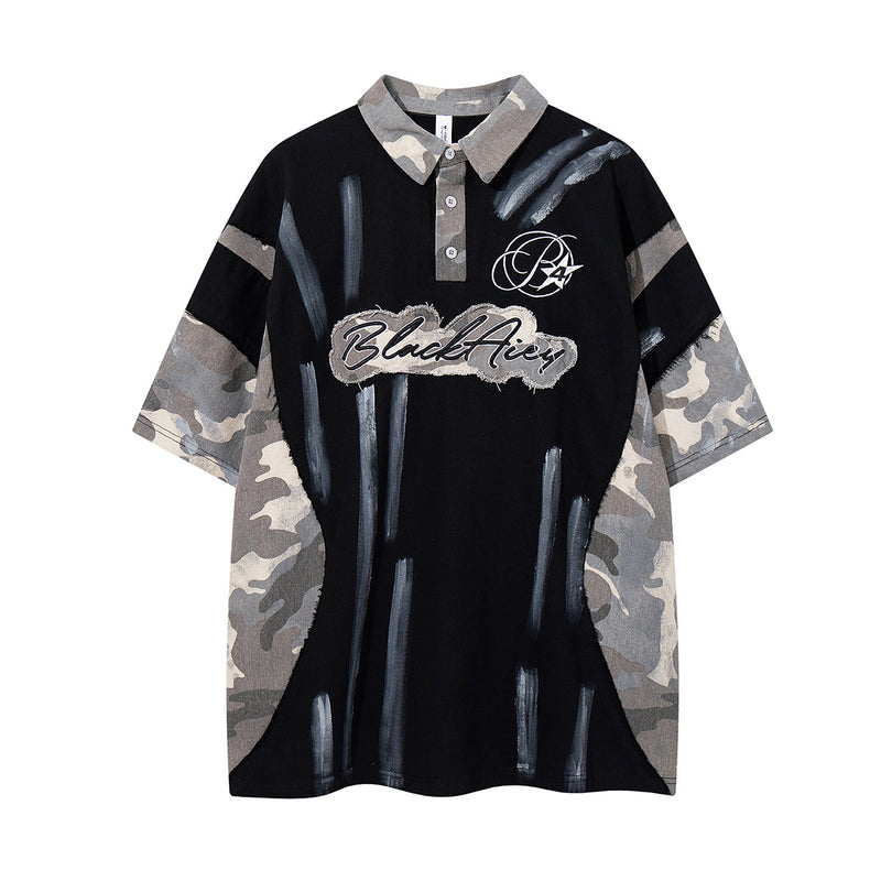 Polo oversize BlackAicy avec manches en patchwork camouflage, imprimé graffiti au pinceau et écusson manuscrit brodé sur la poitrine
