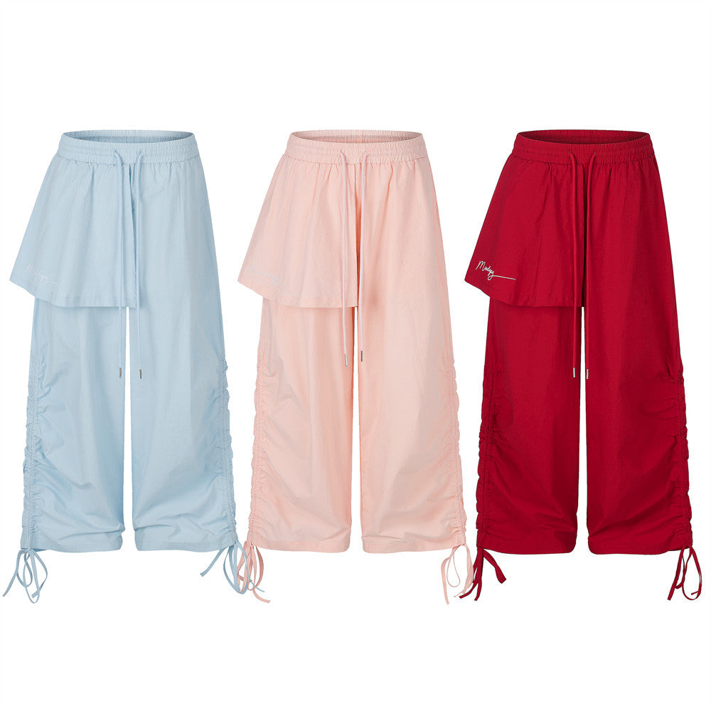 Wide-leg parachute pants with asymmetric layered flap and ruched side drawstring hem in pink, red, and blue