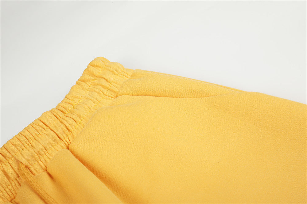 Close-up of yellow sweatpants elastic waistband and smooth fabric texture