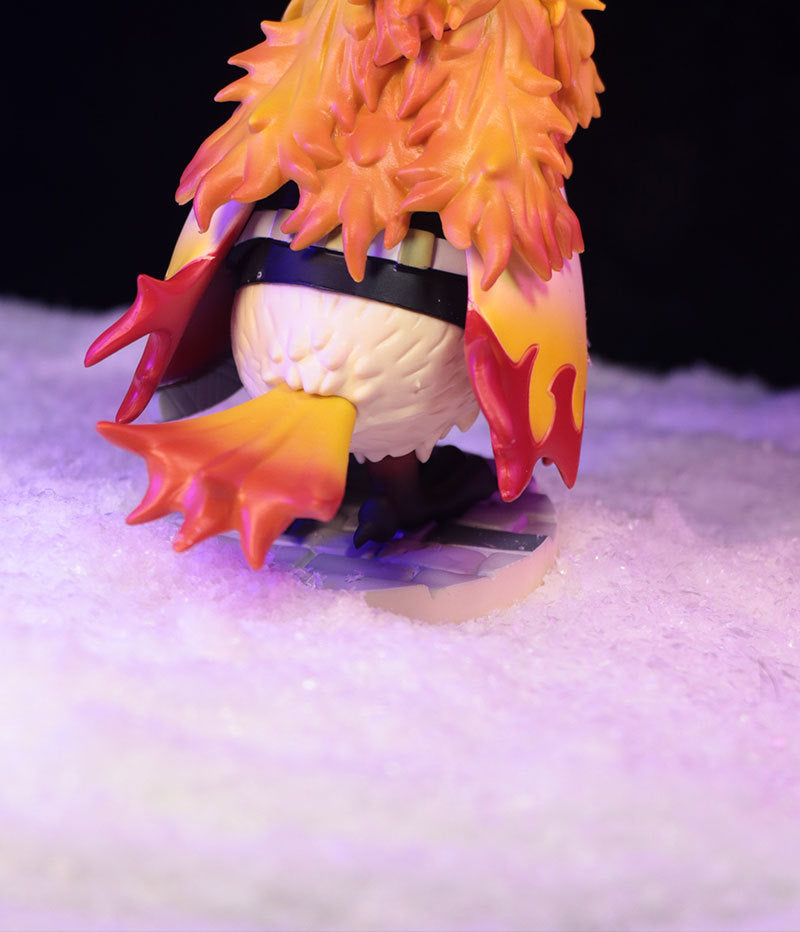 This Demon Slayer collectible features the 11.5cm Owl Cosplay Flame Hashira (Kyojuro Rengoku) figure in red and orange flame-like attire standing on a snowy base, with feather-like textures on its back.