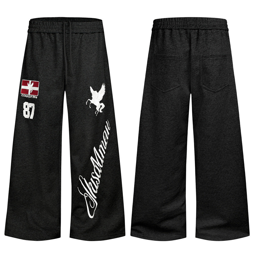 Men's wide-leg sweatpants in black with embroidered Pegasus, flag patch, number 87, and script lettering on the leg