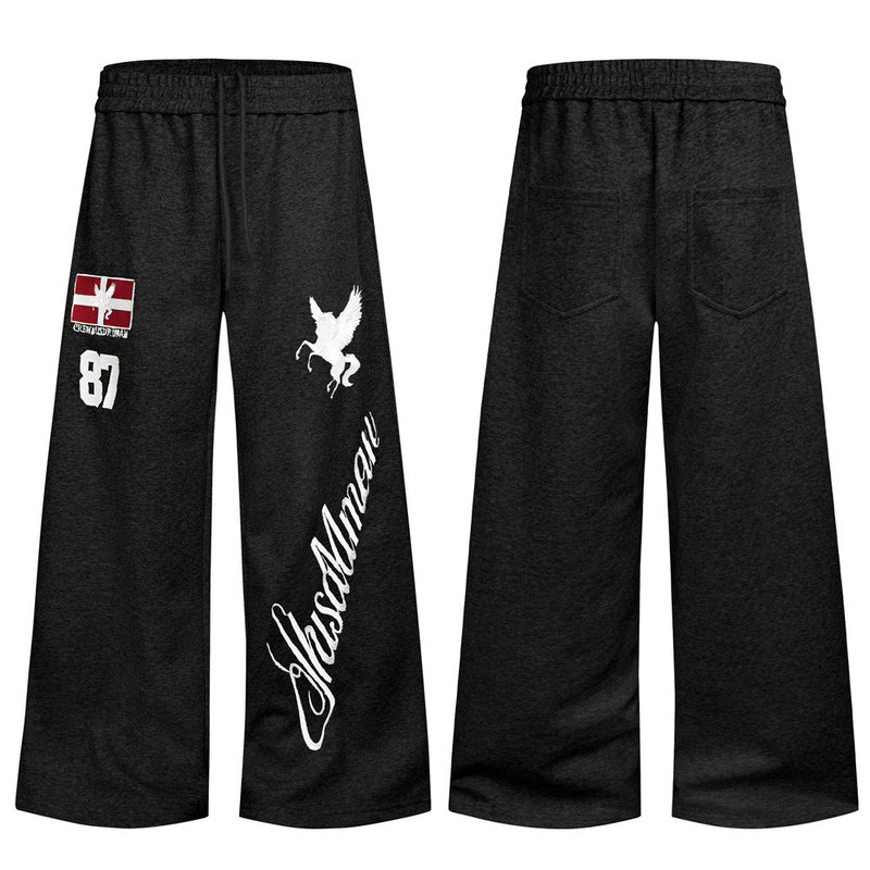 Men's wide-leg sweatpants in black with embroidered Pegasus, flag patch, number 87, and script lettering on the leg