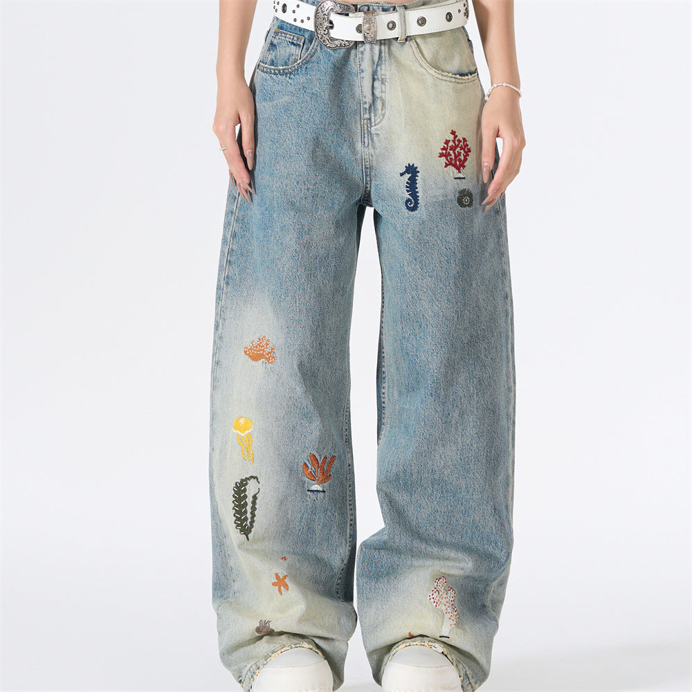 Wide-leg gradient wash jeans with colorful ocean embroidery including seahorses, coral, and jellyfish on blue denim