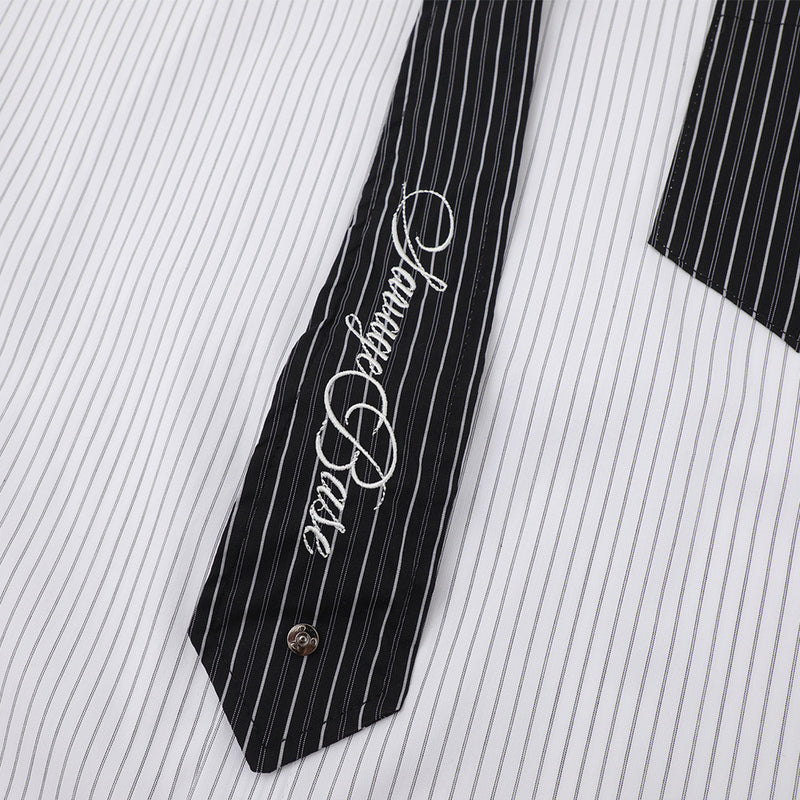 Black contrast tie with white script embroidery on striped shirt front
