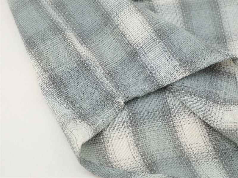 Close-up of a light gray plaid sleeve hem on textured flannel fabric
