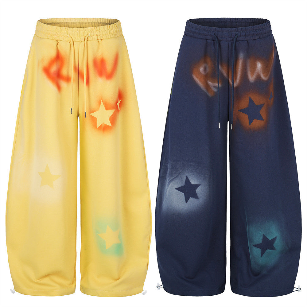 Yellow and navy wide leg sweatpants with star graffiti spray-dye shown front view