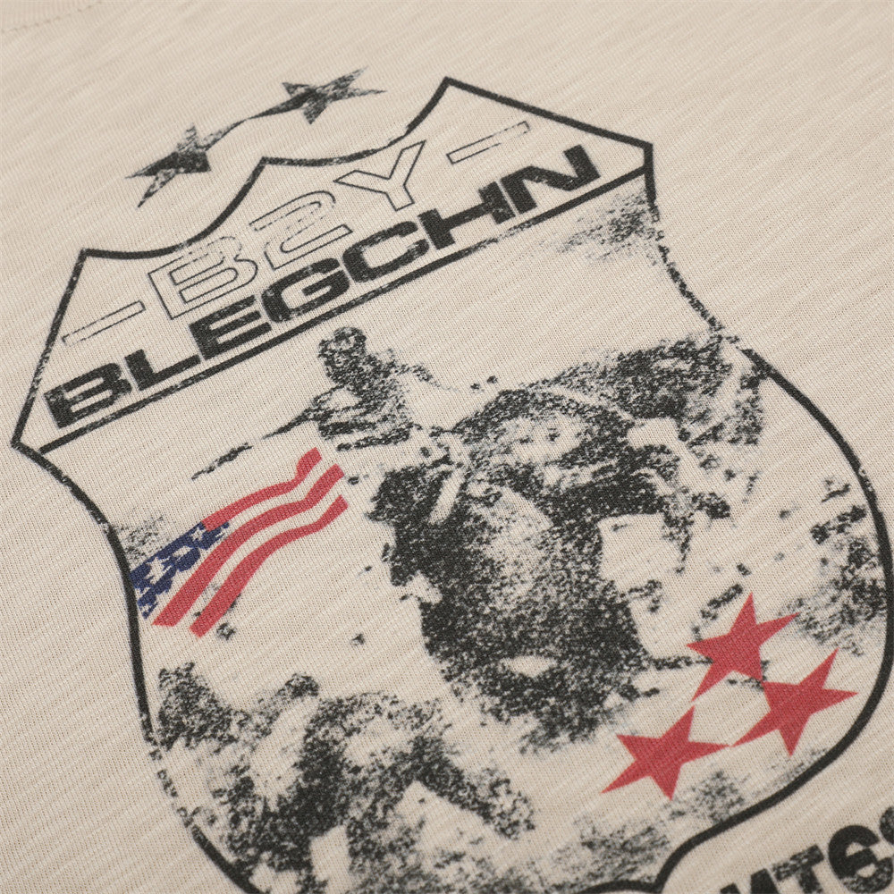Close-up of beige tee front graphic with shield, stars, and flag details