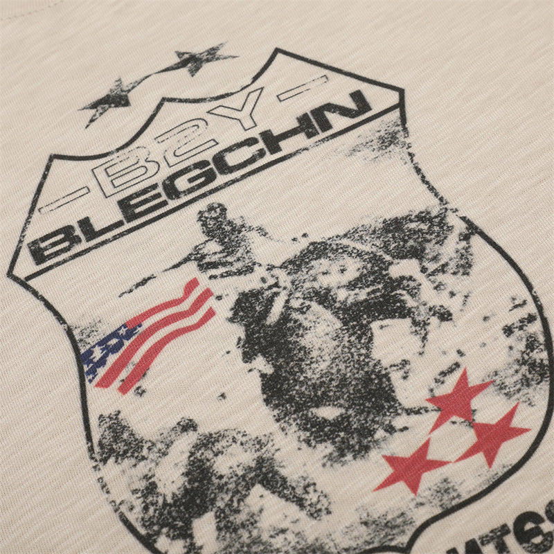 Close-up of beige tee front graphic with shield, stars, and flag details