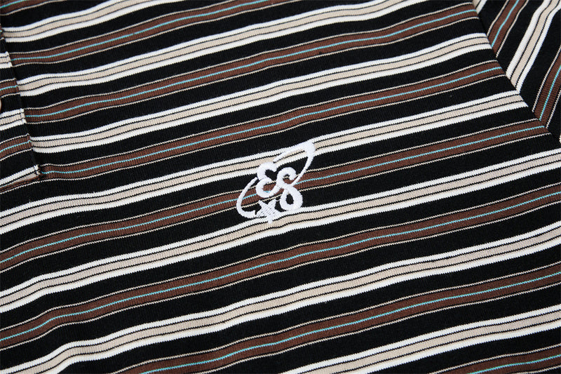 Close-up of embroidered chest logo on black striped Henley shirt