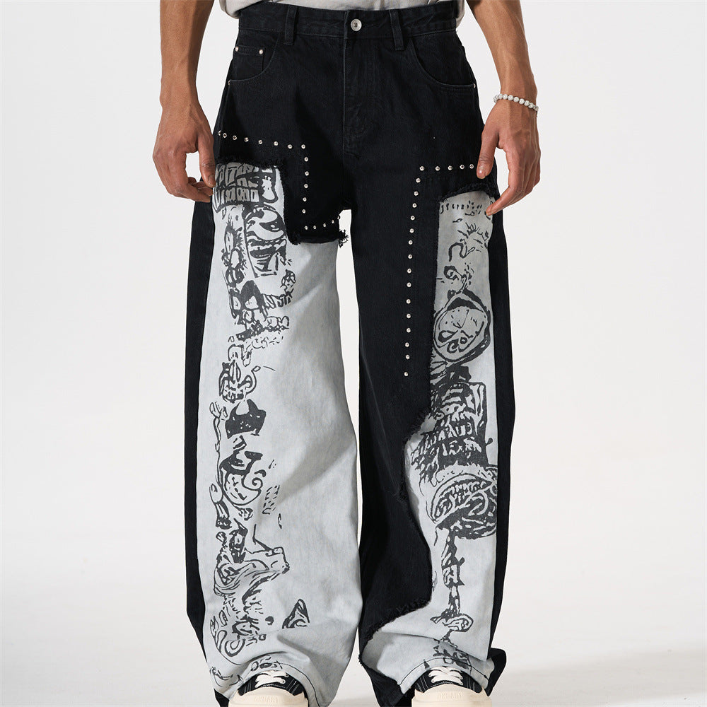 Men's black wide-leg patchwork jeans with grey graffiti print panels and silver stud detailing along raw-edge seams