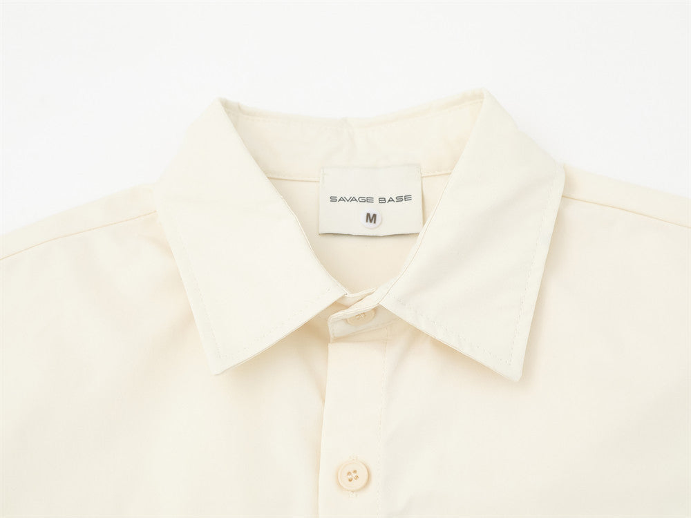 Close-up of cream shirt collar and top button with label and stitched placket