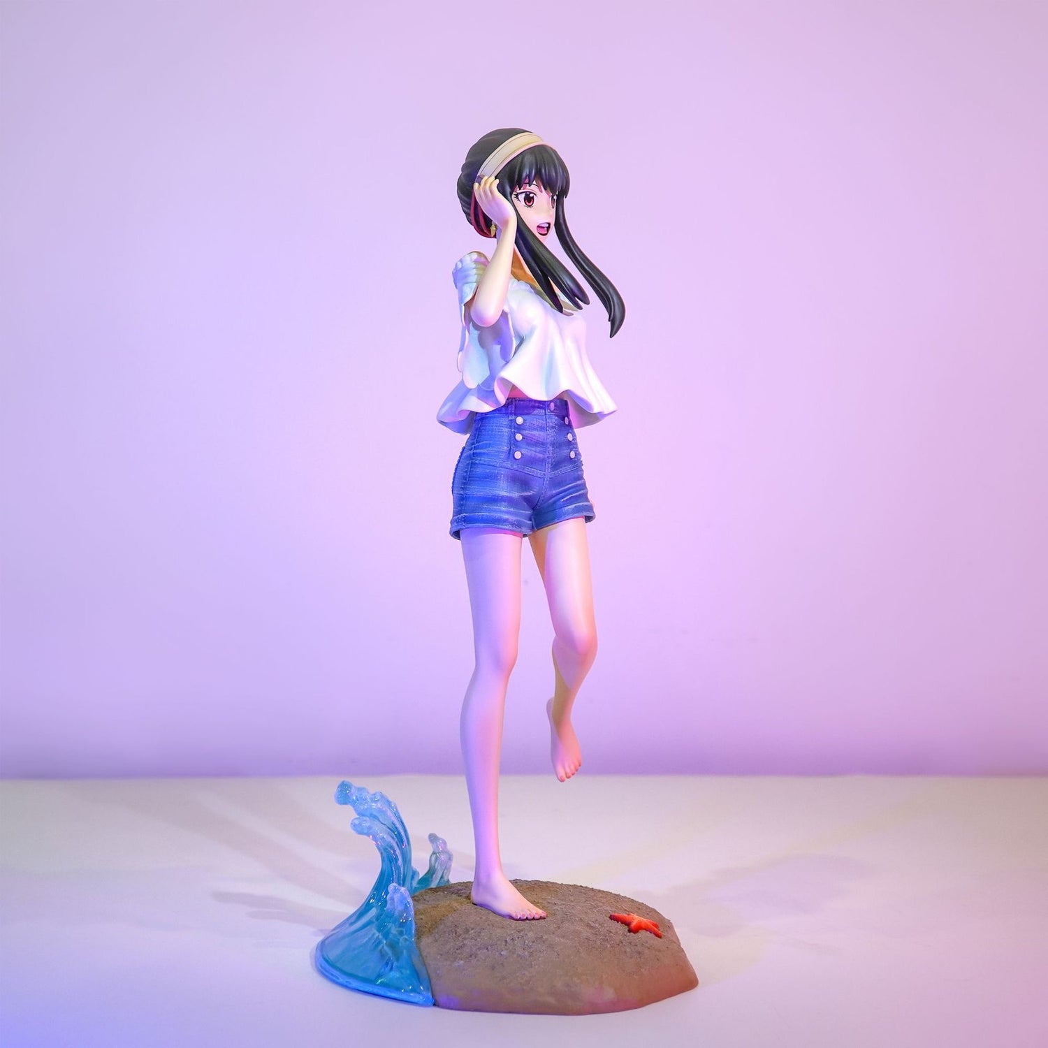 The Shoko Komi Beach Cosplay Figure from Spy × Family depicts a long dark-haired woman, embodying &quot;Komi Can’t Communicate.&quot; She stands on a sandy base with a wave and starfish, dressed in a white blouse and denim shorts—ideal for collectors.