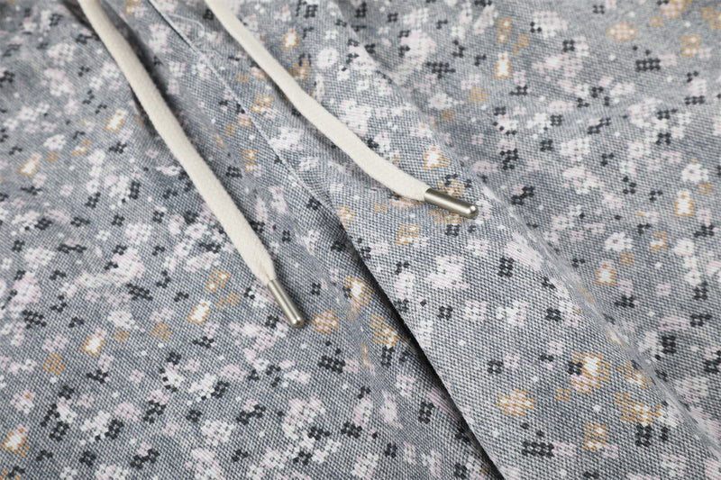 Close-up of cream drawstrings with metal tips on gray floral print pants