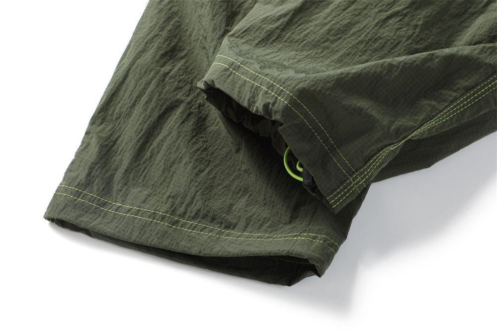 Close-up of an olive pants leg hem showing a concealed green drawcord adjuster
