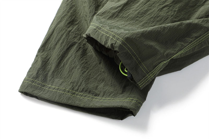 Close-up of an olive pants leg hem showing a concealed green drawcord adjuster