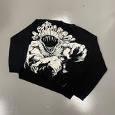 A black Jujutsu Kaisen Premium Yuta Okkotsu-Inspired Full Knit Sweater features a striking back graphic depicting a stylized beast with an open mouth and sharp teeth in white and gray hues, lying flat on a gray surface.