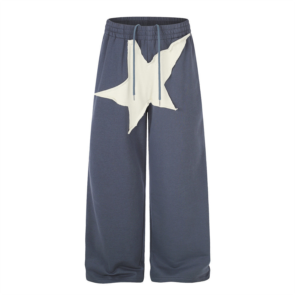 Pantalon de survêtement homme bleu ardoise à jambes larges, avec grand appliqué étoile blanc cassé sur le devant et taille élastique à cordon