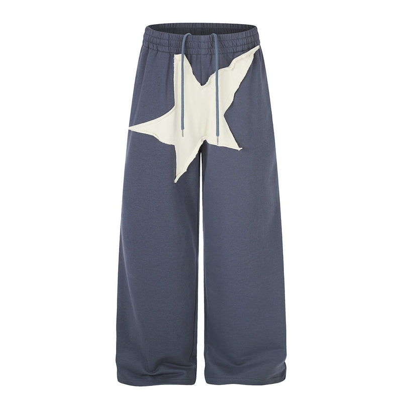 Pantalon de survêtement homme bleu ardoise à jambes larges, avec grand appliqué étoile blanc cassé sur le devant et taille élastique à cordon
