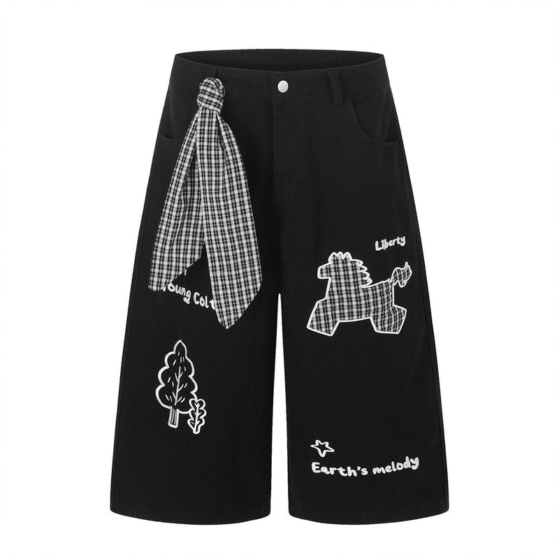 白地にグラフィックプリントを施した、カートゥーン調の馬の刺繍とチェック柄スカーフタイ付きワイドレッグブラックデニムショーツ