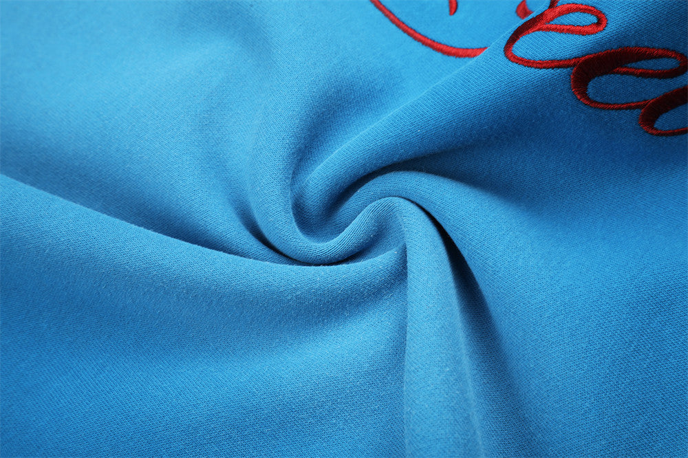 Close-up of blue sweatpants fabric with gathered fold and partial script embroidery