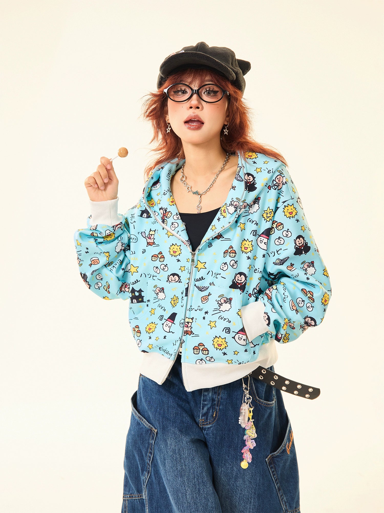 A red-haired person sports a black cap, round glasses, wide-leg jeans, and a whimsical streetwear look featuring Seakoff&