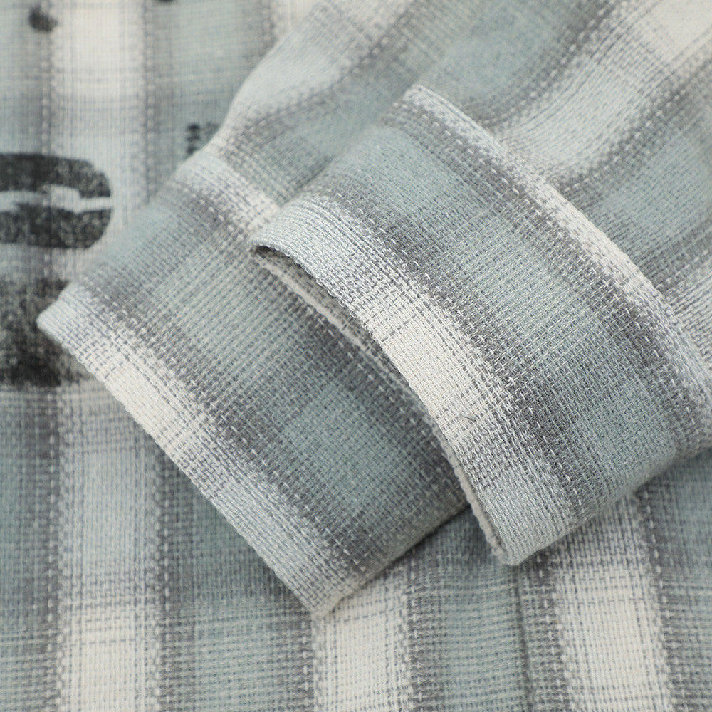 Close-up of a folded sleeve cuff on a light gray plaid flannel shirt