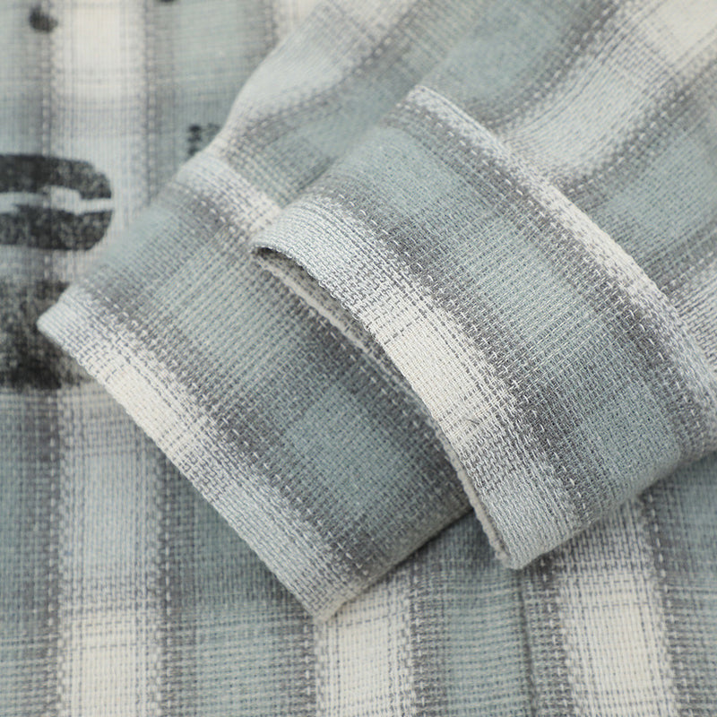 Close-up of a folded sleeve cuff on a light gray plaid flannel shirt