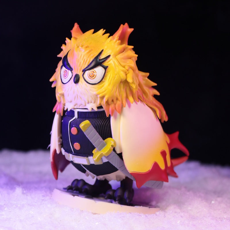 This Demon Slayer collectible flaunts an anime owl character atop a snowy surface with spiky yellow-orange feathers, expressive eyes, a navy-white uniform with buttons, and a small sword—an Owl Cosplay Flame Hashira (Kyojuro Rengoku) Figure on a black backdrop.