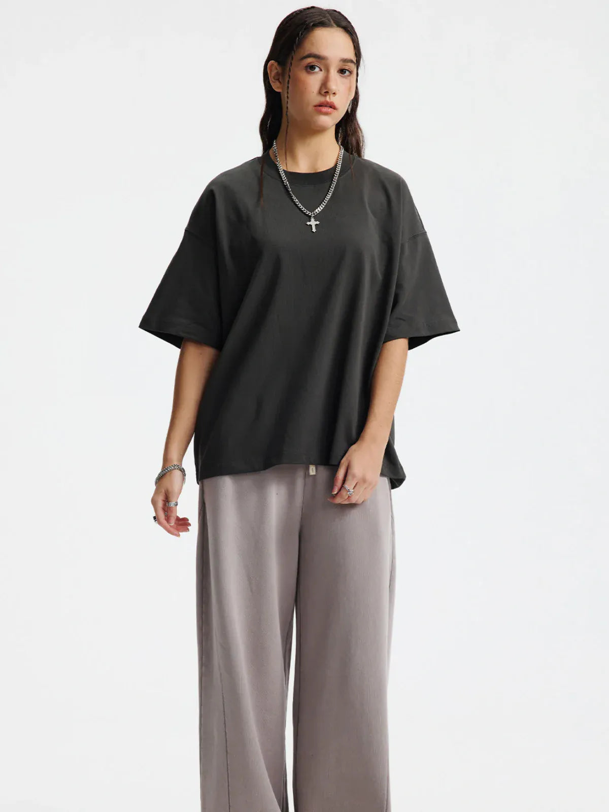 A person wears a Custom Anime Character Charcoal T-Shirt (230GSM, 100% cotton), paired with light gray wide-leg pants and layered necklaces, standing against a plain white background.