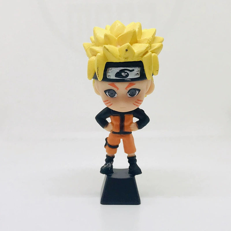 A chibi figurine from Naruto shows an iconic spiky yellow-haired ninja in an orange and black outfit with a headband, standing on a black base. It complements any Naruto Ninja Masters Keycap Set for mechanical keyboards.