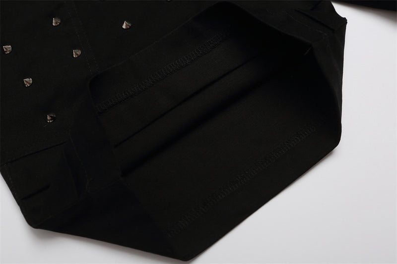 Close-up of black shorts lower leg with studded front panel and layered hem