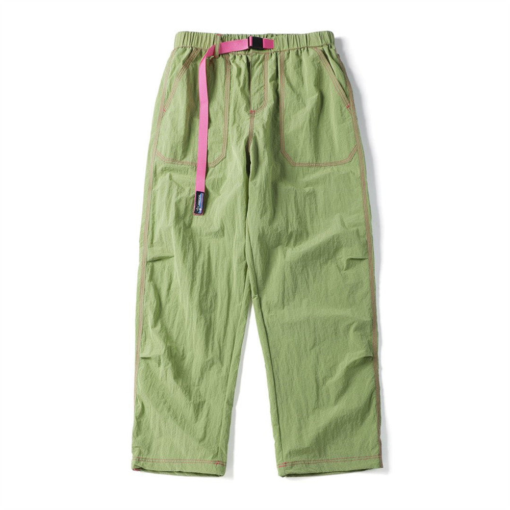 Front view of light green crinkled parachute pants with pink contrast stitching and drawcord