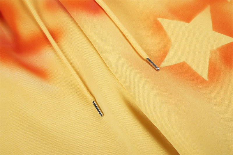 Close-up of yellow sweatpants drawstrings and star print with orange spray-dye
