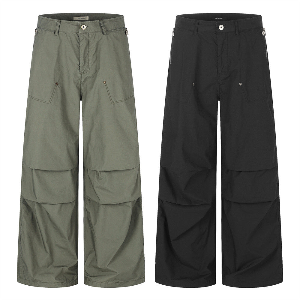 Men's wide-leg parachute cargo pants in army green and black with layered panel construction and zip pockets