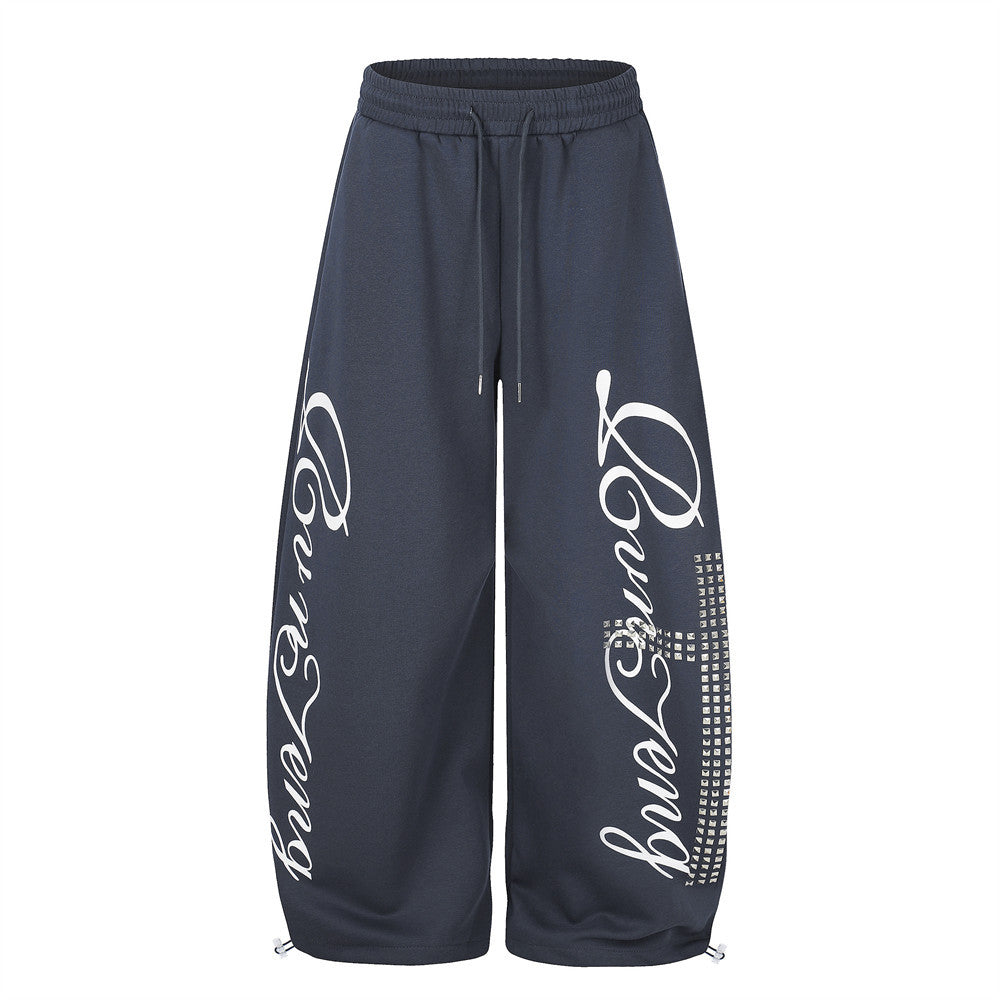 Men's oversized wide leg sweatpants in navy blue with cursive script graphic print and rhinestone cross detail on front leg p
