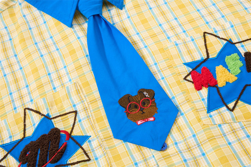 Close-up of blue tie and embroidered cartoon dog motifs on yellow plaid shirt