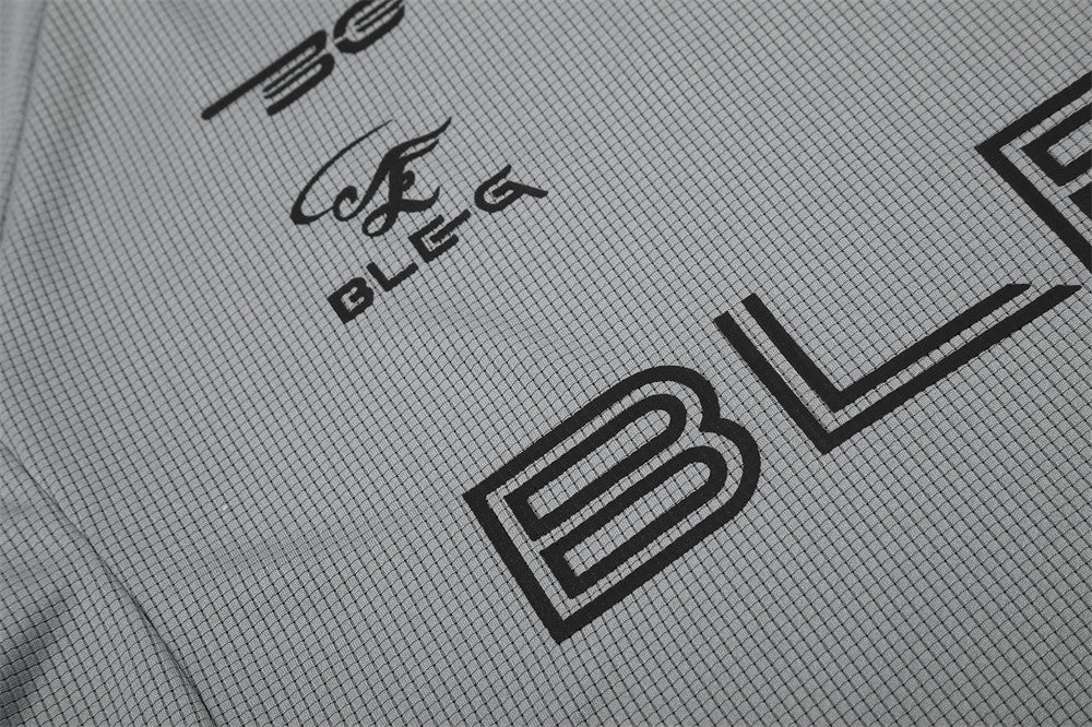Close-up of gray shirt graphic showing BLEG lettering and large B print