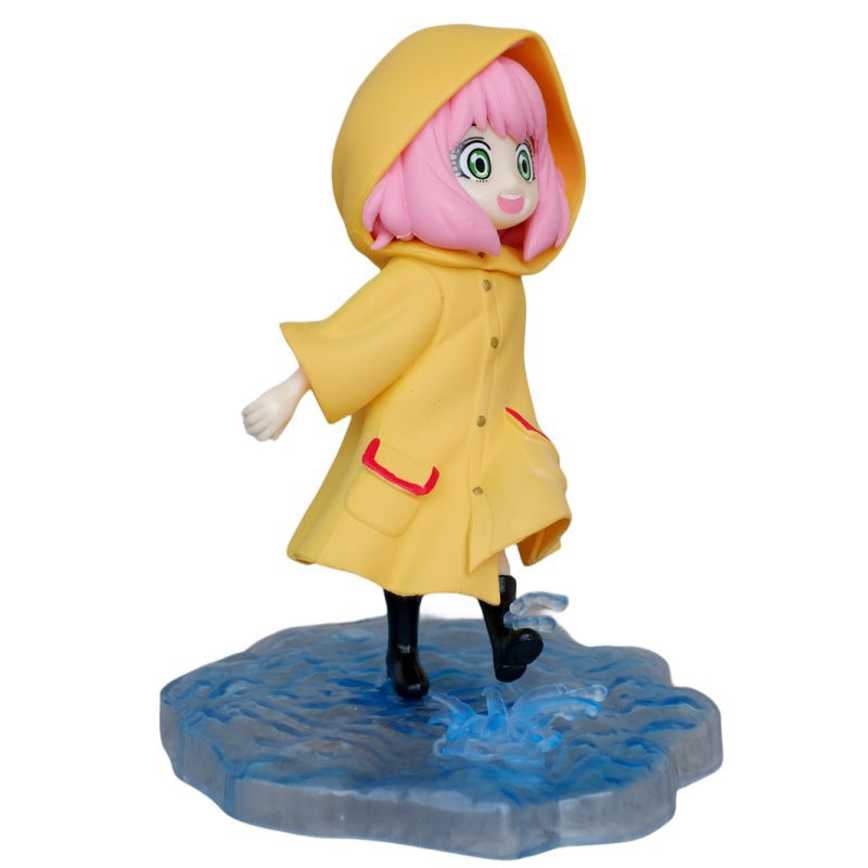 The Anya Forger Yellow Raincoat Figure from Spy × Family is a cute PVC anime collectible featuring pink-haired Anya in a yellow raincoat and hood, standing on a blue water-representing base. She wears black boots and smiles with one foot playfully raised as if splashing in a puddle.