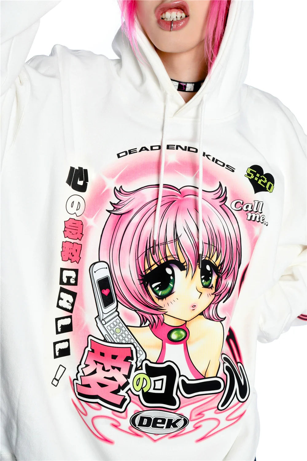 A person with pink hair wears the Seakoff Y2K Aesthetic Anime Hoodie, featuring a pink-haired anime character with green eyes and a kawaii phone. The design includes Japanese and English text, along with "DEAD END KIDS" in a retro manga style.