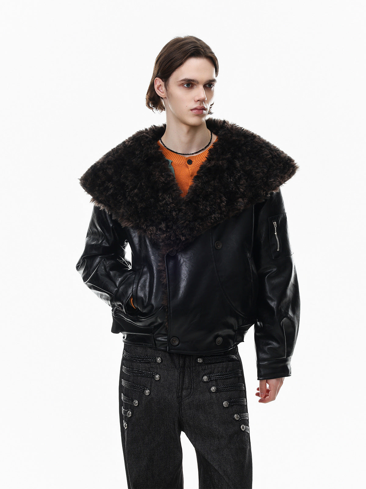 Men's oversized black faux leather bomber jacket with large faux shearling lapel collar, cropped fit, worn over an orange kni