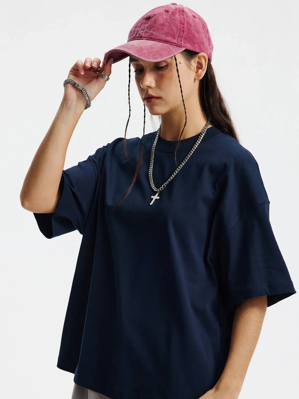 Wearing a Custom Anime Character Navy T-Shirt - Personalized 230GSM 100% Cotton Tee, a silver chain with a cross pendant, and a pink baseball cap, the person looks down with one hand touching the cap.