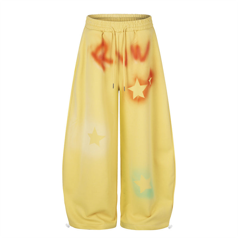 Yellow wide leg sweatpants with star graffiti spray-dye shown front view