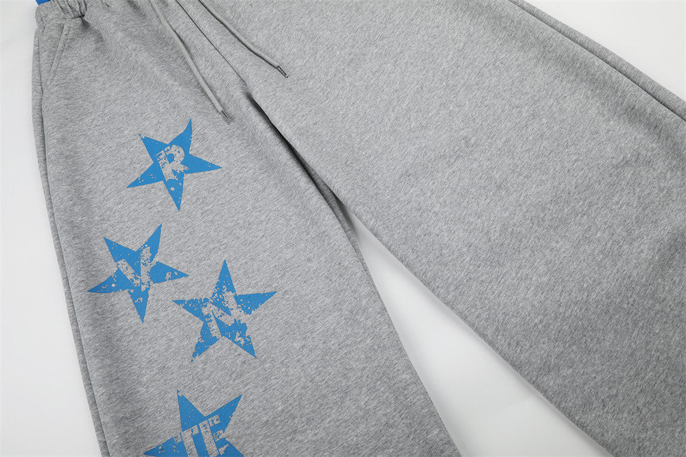 Angled view of gray sweatpants leg with blue star print and drawstring waist