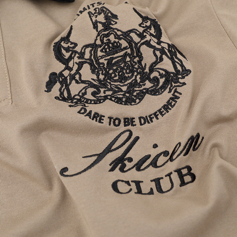 Close-up of khaki polo shirt chest graphic with black embroidered lettering